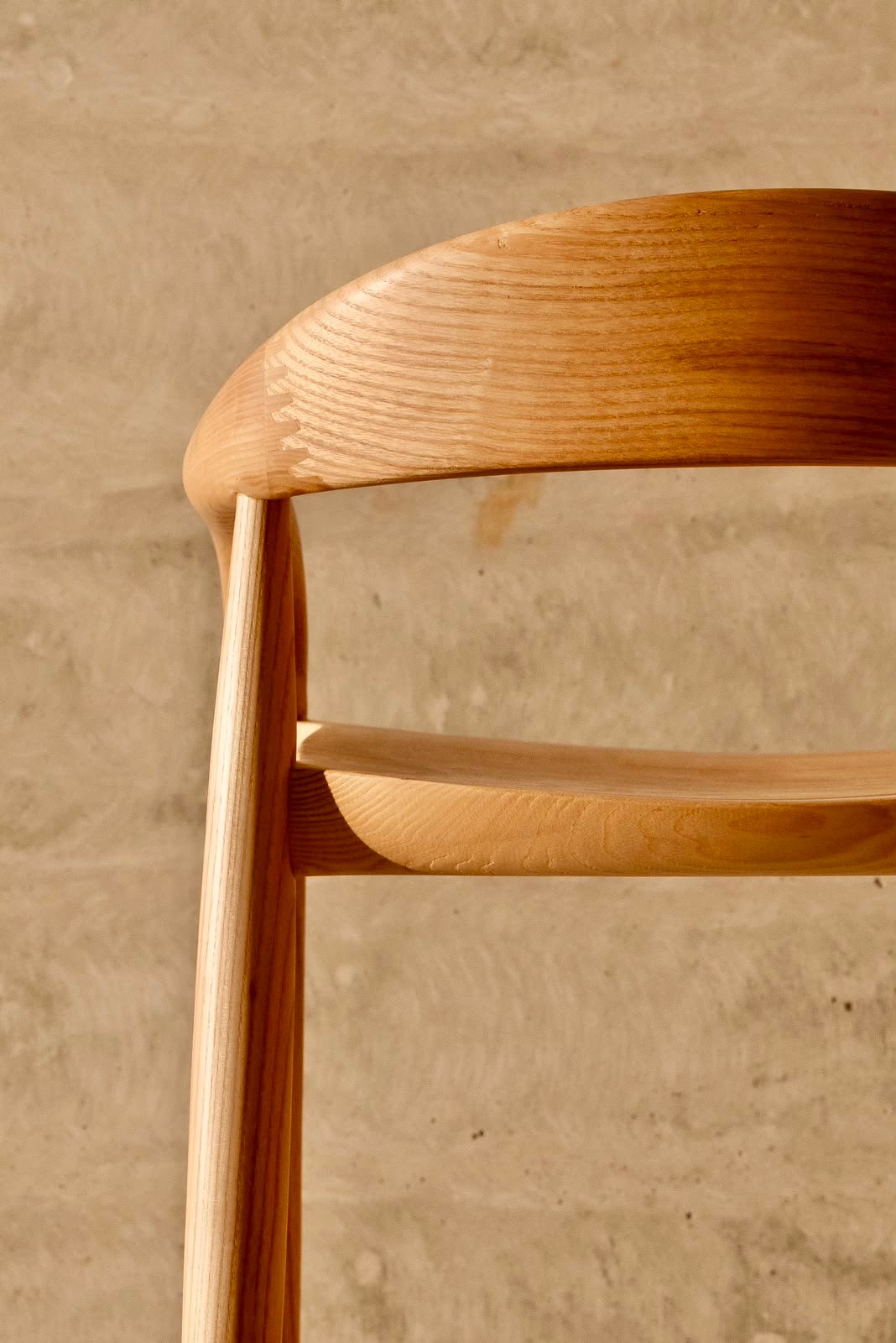 Close detail of the ash backrest and arm, showing the flowing timber grain and hand-finished surface